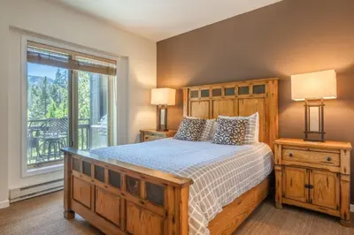 a bedroom with a wooden bed and a window at Mammoth Green #210 - Nearly Ski-in Ski-Out 2 Bedroom 2 Bath, Sleeps 6 on Golf Course in Mammoth Lakes