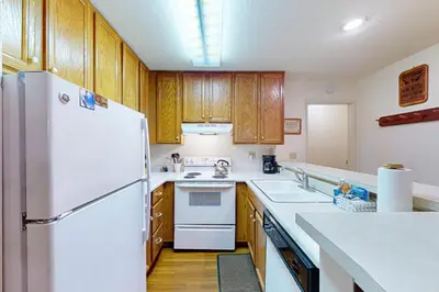 a kitchen with a white refrigerator and wooden cabinets at Chamonix 36 in Mammoth Lakes