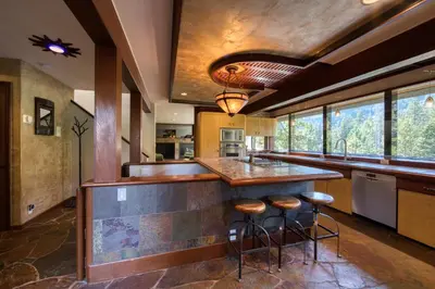 a kitchen with a counter and stools at a bar at Spire Chalet at Alpine Meadows - 4BR W Hot Tub and Ski Shuttle in Alpine Meadows