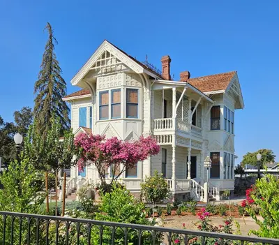 a large white house with a fence in front of it at The JD Hyde Historic Inn in Visalia