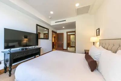 a bedroom with a large white bed and a flat screen tv at Iron Horse Lodge South 408 by East West Hospitality in Truckee