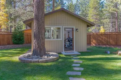a small shed with a tree in the yard at Luxury Single Level, Great Location, Hot Tub, Arcade in South Lake Tahoe