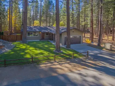 a home in the woods with a fence at Luxury Single Level, Great Location, Hot Tub, Arcade in South Lake Tahoe
