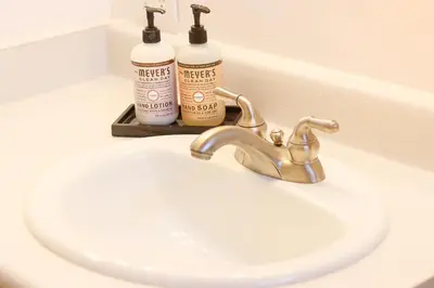 a white bathroom sink with two bottles ofodorizers on it at 1 BR Orchard Cottage - Gateway to Two National Parks! in Visalia