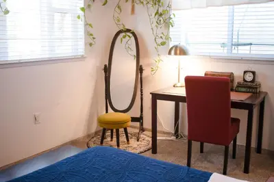 a bedroom with a table and a chair and a mirror at 1 BR Orchard Cottage - Gateway to Two National Parks! in Visalia