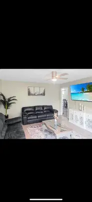 a living room with a black couch and a flat screen tv at Beautiful Home & Pool in Fresno