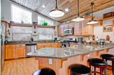 a kitchen with wooden cabinets and a large island with bar stools at Serenity Pines in Yosemite West