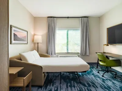 a hotel room with a bed and a couch at Fairfield Inn & Suites Hanford in Hanford