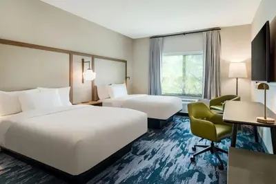 a hotel room with two beds and a desk and a chair at Fairfield Inn & Suites Hanford in Hanford