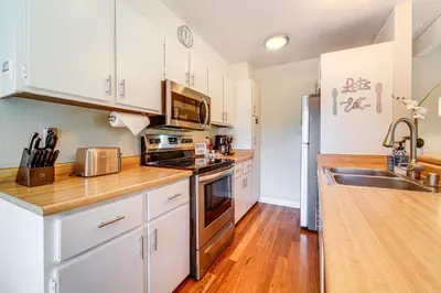 a kitchen with white cabinets and a wooden counter top at 5 Mi to Northstar Skiing Bear Den Home with Decks in Kings Beach