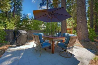 a table with chairs and an umbrella on a patio at Bright Tahoe Home with Private Backyard Near Beach in Tahoe City