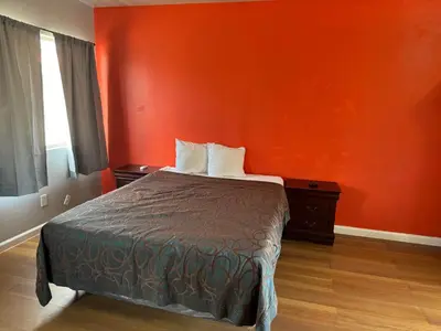a bedroom with a bed with an orange wall at Coalinga Motel in Coalinga