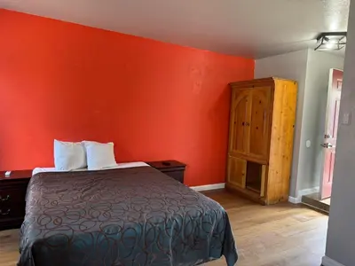 a red room with a bed and a wooden cabinet at Coalinga Motel in Coalinga