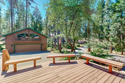 two benches sitting on a deck with a house at Tranquil Pines Retreat in Shaver Lake