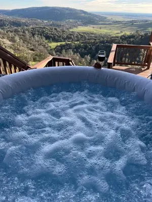 a bath tub filled with water with a glass of wine at Breathtaking view of the Hills with HotTub, Pool and Pool Table in Marble Mountain