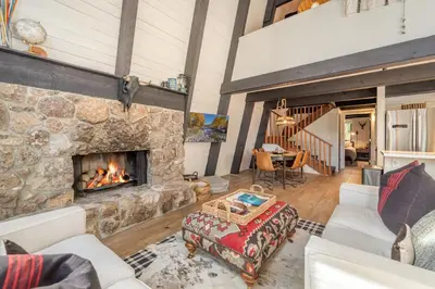 a living room with a large stone fireplace at Mid Century Modern A-Frame Cabin at Northstar in Truckee