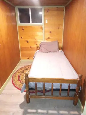 a bed in a room with a wooden wall at Baltyr Cabin in Miramonte