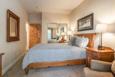 a bedroom with a large bed and a chair at Mammoth Gateway Village #1 - Highly Updated Townhome - Walk To Village 3 Bed+Loft, Sleeps 10 in Mammoth Lakes