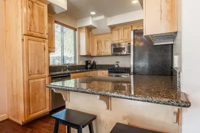 a kitchen with wooden cabinets and a granite counter top at Mammoth Gateway Village #1 - Highly Updated Townhome - Walk To Village 3 Bed+Loft, Sleeps 10 in Mammoth Lakes