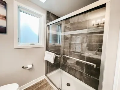 a bathroom with a glass shower stall and a toilet at Beautiful and Elegant River Front Cottage in Reno