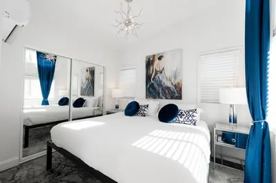 a white bedroom with two beds and blue curtains at Beautiful Courtyard Cottage Sapphire in Reno