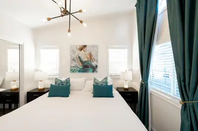 a white bedroom with a large bed with blue pillows at Beautiful Courtyard Cottage Emerald in Reno