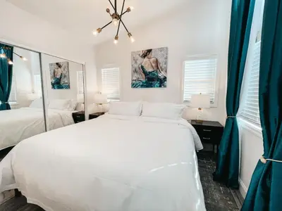 a white bedroom with two beds and a mirror at Beautiful Courtyard Cottage Emerald in Reno