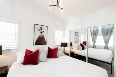 a white bedroom with two beds with red pillows at Elegant Courtyard Cottage Ruby in Reno
