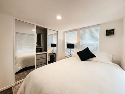 a bedroom with a large white bed and a mirror at Beautiful Downtown Cottage Onyx in Reno
