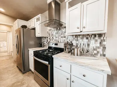 a kitchen with white cabinets and a black stove top oven at Beautiful Private Cottage Sunstone in Reno