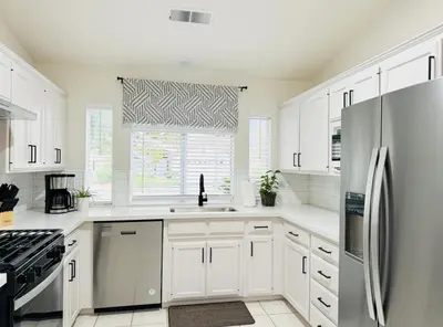 a white kitchen with white cabinets and a window at Charming Retreat in CA Valley in Fresno