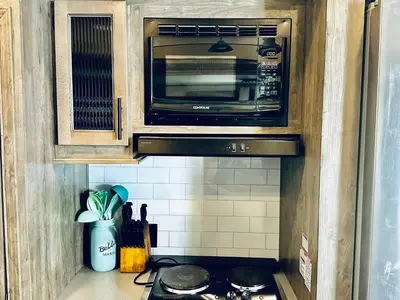 a kitchen with a stove and a microwave at Puffy Panda RV-Hot Tub-Sleeps 2 in Ahwahnee