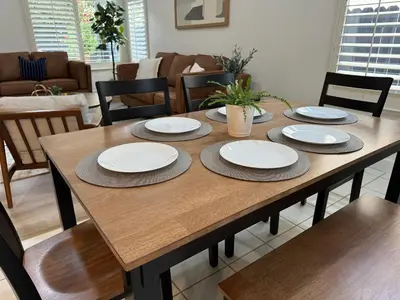 a wooden table with plates and chairs in a living room at Charming retreat in CA Valley in Fresno