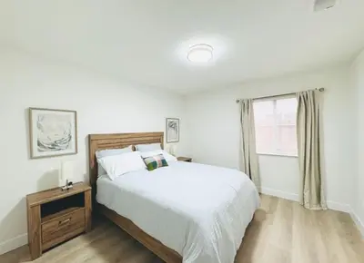 a white bedroom with a bed and a window at Charming retreat in CA Valley in Fresno