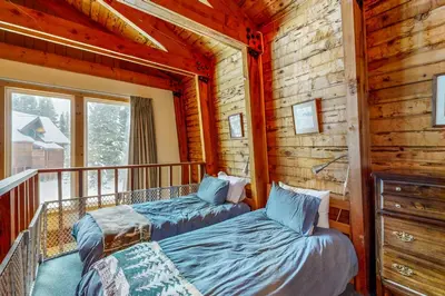 a log cabin bedroom with two beds on a balcony at The Calder Cabin in Soda Springs