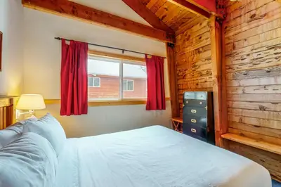 a bedroom with a bed and a window with red curtains at The Calder Cabin in Soda Springs