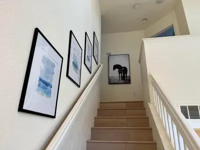 a hallway with pictures on the walls and stairs at Remodeled 3B2B Bright House with a King Suite in Sacramento