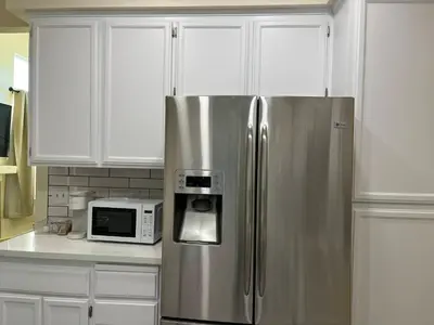 a stainless steel refrigerator in a kitchen with white cabinets at Remodeled 3B2B Bright House with a King Suite in Sacramento