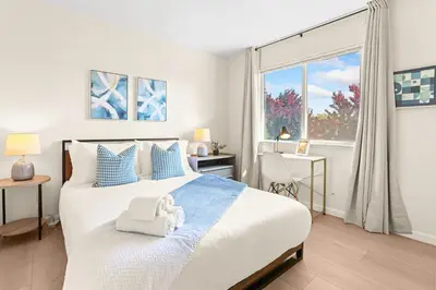 a bedroom with a bed with blue pillows and a window at Remodeled 3B2B Bright House with a King Suite in Sacramento