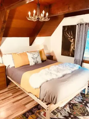 a bedroom with a large bed with a chandelier at Happy Cabin Near Snow and Lake with Hot Tub, Dogs OK in Tahoe Vista