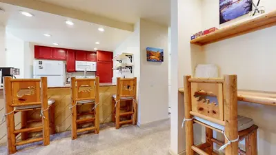 a kitchen with red cabinets and wooden stools at Snowcreek II #279 condo in Mammoth Lakes