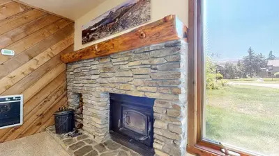 a stone fireplace in a house with a window at Snowcreek II #279 condo in Mammoth Lakes
