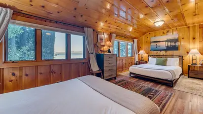 two beds in a room with wooden walls and windows at Lakefront Haven by AvantStay Minutes to Ski Resorts Private Dock in Homewood