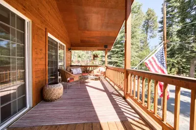 a wooden porch with an american flag on it at Knotty and Nice - 4BR w Private Hot Tub, Close to Lake in Tahoe Vista
