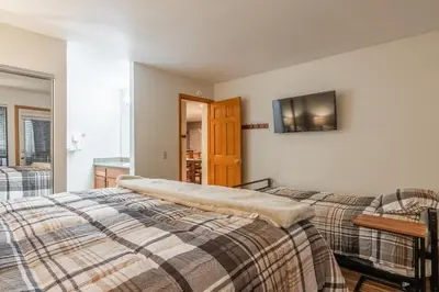 a bedroom with two beds and a tv on the wall at Summit #269 - 2 Bedrm 2 Bathrm Condo - Walk To Eagle Lodge Lifts in Mammoth Lakes