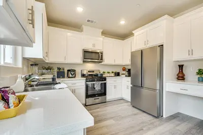 a kitchen with white cabinets and a stainless steel refrigerator at Chowchilla Home with Private Patio! in Chowchilla