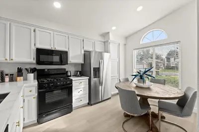 a kitchen with white cabinets and a table with chairs at Recently Upgraded House with King Suite, quiet NBHD, Fast Wifi, and Yard in Elk Grove