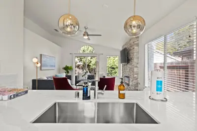 a kitchen with a sink and a living room at Recently Upgraded House with King Suite, quiet NBHD, Fast Wifi, and Yard in Elk Grove