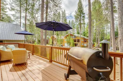 a deck with a grill and chairs and an umbrella at Snowshoe and Sled On-Site! Soda Springs Cabin in Soda Springs
