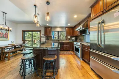 a kitchen with wooden cabinets and a stainless steel refrigerator at Northstar Family Retreat on Shuttle Line with Deck in Truckee